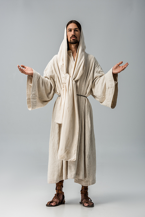 bearded man in hood standing with outstretched hands isolated on grey