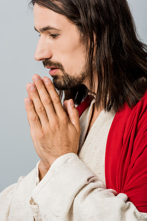 bearded and handsome man with praying hands isolated on grey