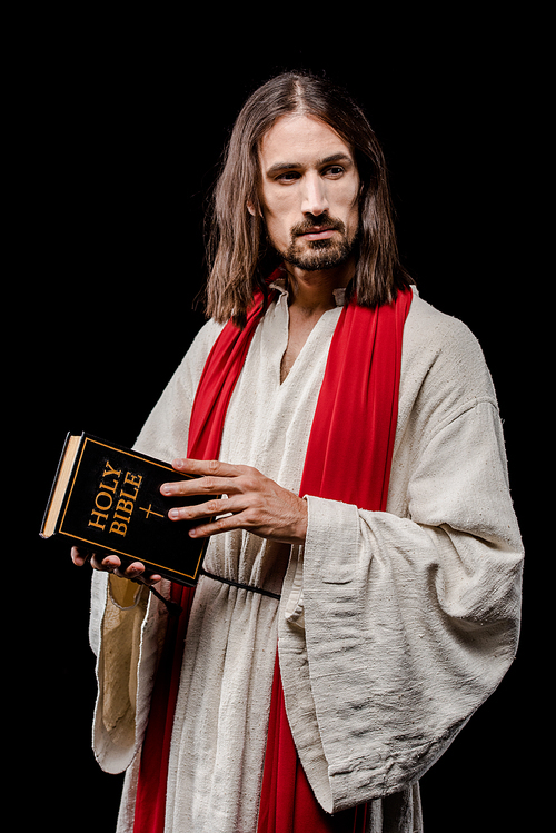 handsome man in jesus robe holding holy bible isolated on black