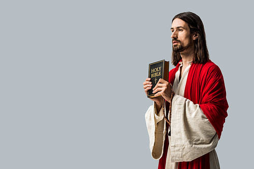 handsome bearded man holding holy bible isolated on grey