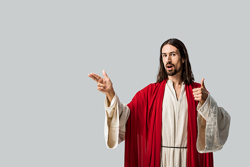 surprised man in jesus robe showing thumb up and gesturing isolated on grey