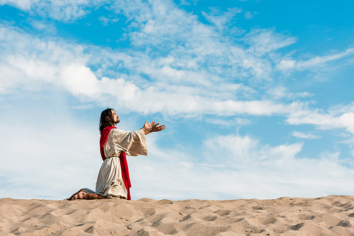 jesus praying on knees in desert against sky