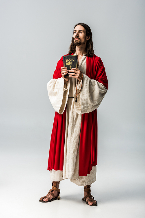 handsome religious man holding holy bible on grey