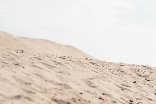 selective focus of wavy sand against sky with clouds in desert