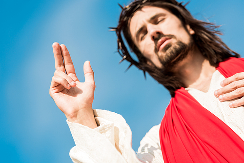 low angle view of man with closed eyes gesturing against blue sky