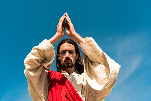 low angle view of jesus with praying and  against blue sky