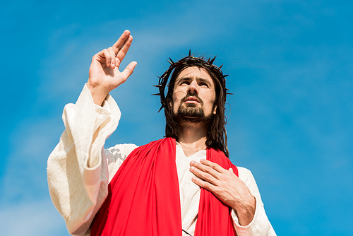 low angle view of man with hand on chest gesturing against blue sky