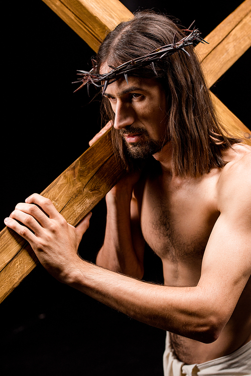 jesus in wreath with spikes holding wooden cross isolated on black