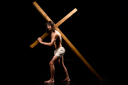 shirtless jesus in wreath holding wooden cross and standing on black