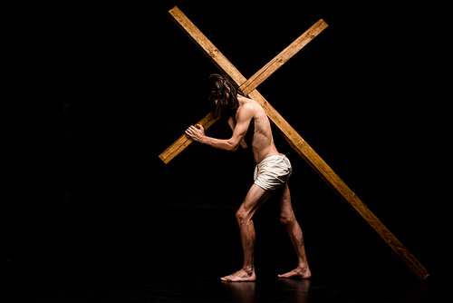 shirtless jesus walking with wooden cross on black