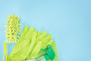 top view of green rubber gloves, sponge, rag and spray bottle with detergent on blue background with copy space