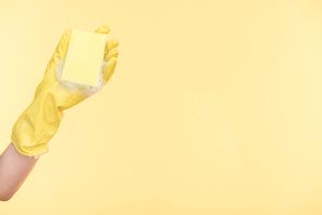 cropped view of cleaner in yellow rubber glove holding sponge with bubbles on yellow background