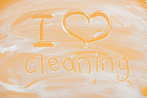 i love cleaning handwritten lettering written on glass with white foam on orange background