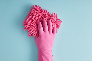 cropped view of housekeeper in rubber glove holding pink rag on blue