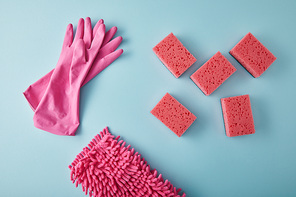 top view of pink rubber gloves, rag and sponges for house cleaning on blue