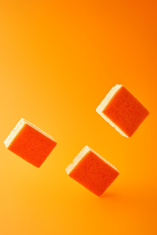 falling sponges for dish washing on orange