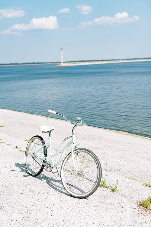 bicycle on asphalt near blue river in summer in sunshine