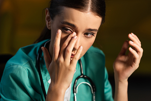 attractive and tired nurse in uniform crying during night shift