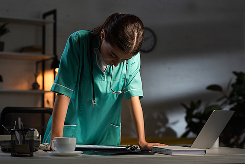 attractive nurse in uniform with stethoscope looking down during night shift