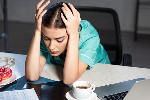 attractive nurse in uniform sitting at table and sleeping during night shift