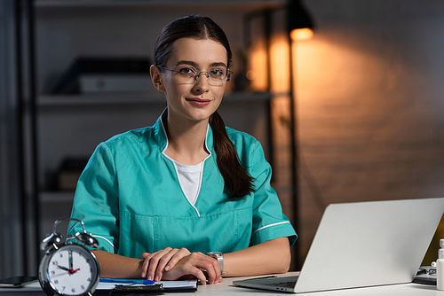 attractive nurse in uniform and glasses sitting at table and  during night shift