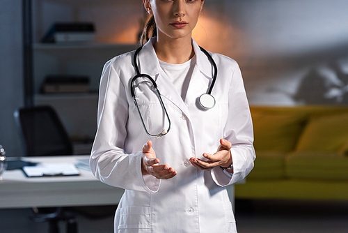 cropped view of doctor in white coat with stethoscope during night shift
