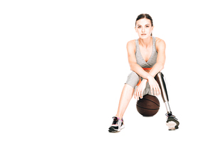 front view of disabled sportswoman sitting on basketball ball isolated on white