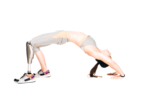 side view of disabled sportswoman with prosthesis doing bridge exercise isolated on white