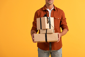 cropped view of happy man holding presents isolated on orange
