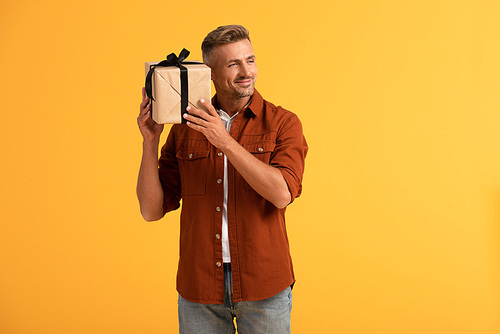 happy man smiling and holding present isolated on orange