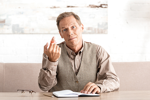 confused retired man with red bow on finger near notebook