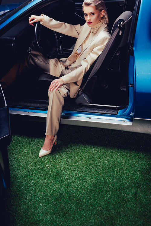 high angle view of attractive and stylish woman in suit sitting in retro car