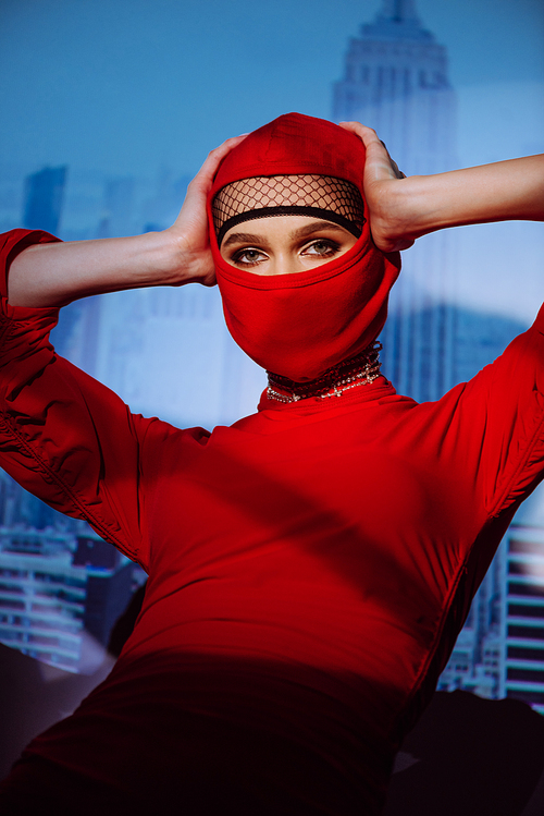 stylish woman in red dress and balaclava on city background