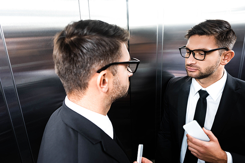 high angle view of businessman in suit looking at mirror in elevator