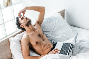 high angle view of handsome and pensive bi-racial man with laptop in morning