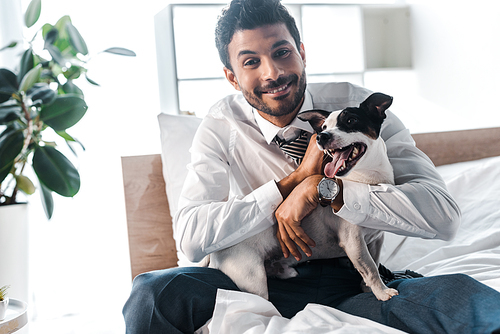 smiling bi-racial businessman stroking Jack Russell Terrier in morning at home