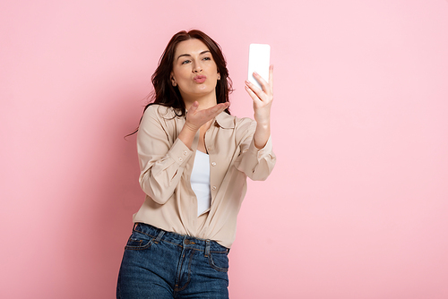 Beautiful woman  while taking selfie with smartphone on pink background, concept of body positive