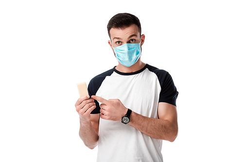man in medical mask pointing with finger at soap bar isolated on white