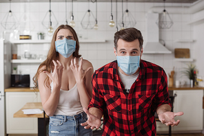 irritated couple in medical masks screaming and gesturing while 