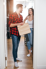 young man holding paper bag with takeaway food while looking at smiling girlfriend