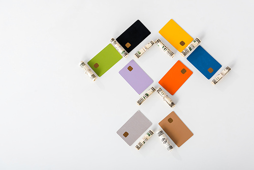 flat lay with multicolored credit card templates near cash rolls on white