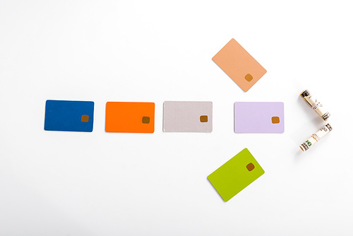 top view of colorful credit card templates and cash rolls on white