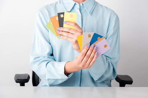 cropped view of woman holding multicolored credit card templates in hands isolated on white
