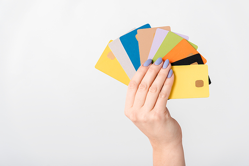 cropped view of woman holding multicolored credit card templates in hand isolated on white