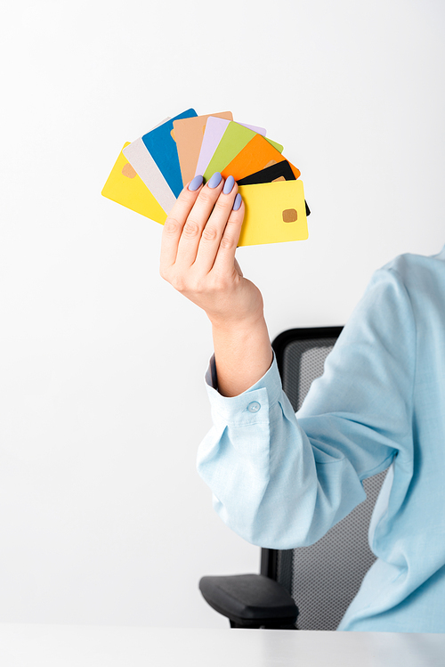 cropped view of woman holding multicolored credit card templates in hand isolated on white