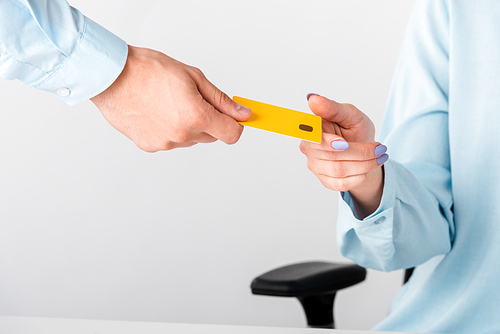 cropped view of man giving yellow credit card template to woman isolated on white