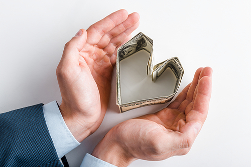 top view of businessman near heart-shaped dollar banknotes on white
