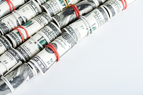 dollar banknotes in cash rolls with colorful rubber bands on white