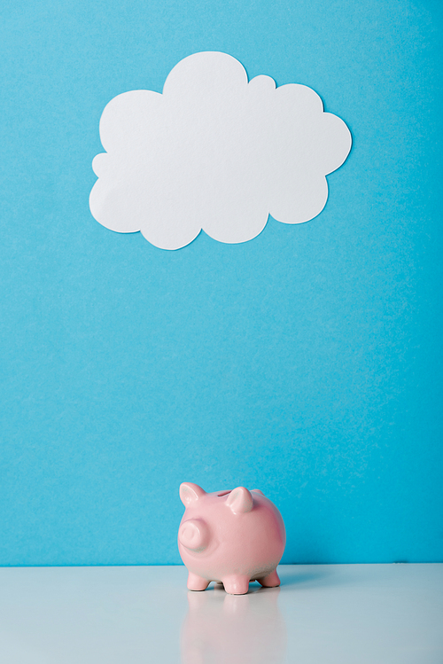 pink piggy bank near white cloud on blue with copy space