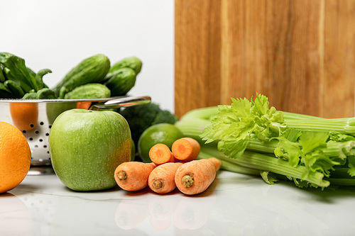 tasty fruits near ripe, fresh vegetables and wooden cutting board on white
